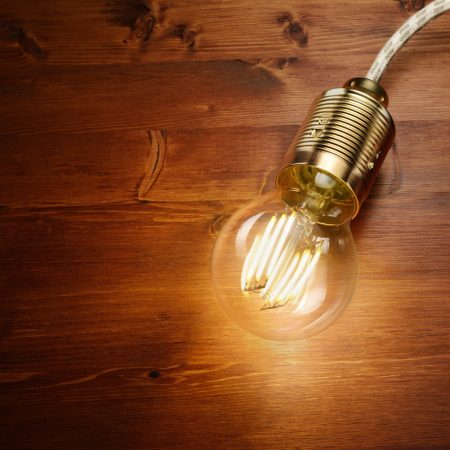 LED filament classic styled bulb on wooden board background.